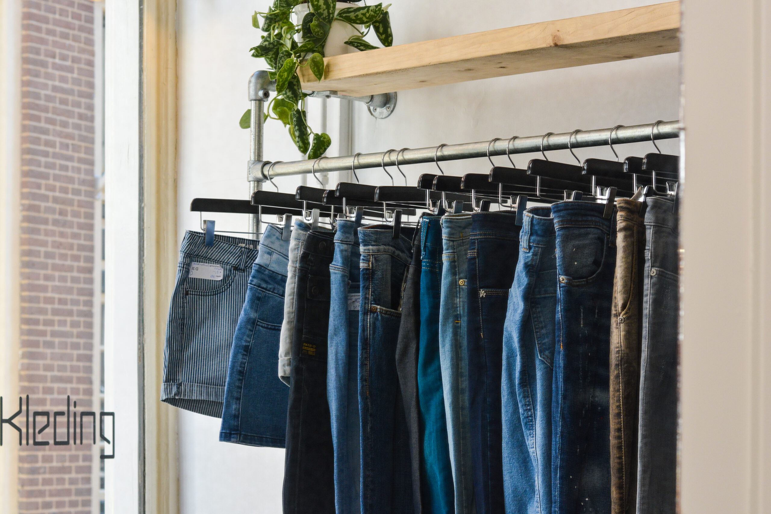 Uitzicht op de collectie tweedehands broeken en denim shorts bij de entree van Marleen's kledingwinkel in Zutphen.